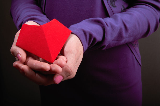 象征女性手掌中的心。女人手中的红纸心。特写镜头图片下载