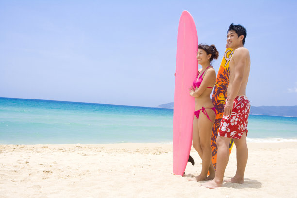 拿着冲浪板站在沙滩上的人图片下载