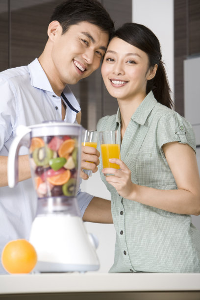 青年夫妇在厨房做鲜榨果汁图片下载