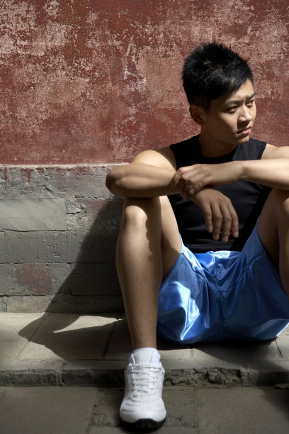 男运动员坐在墙下图片下载