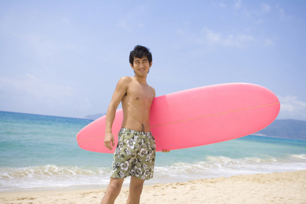 拿着冲浪板的男孩站在沙滩上图片下载