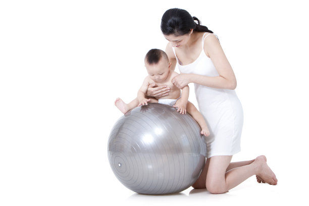 母亲指导婴儿在健身球上玩图片下载