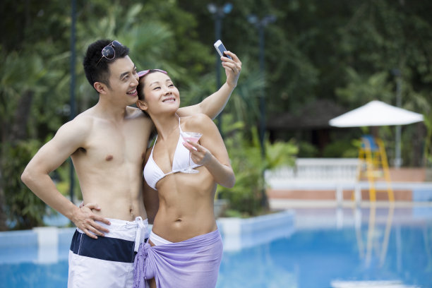 游泳池边拍照的年轻情侣图片下载