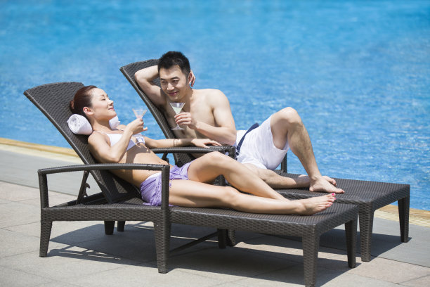 游泳池边晒日光浴的年轻情侣图片下载