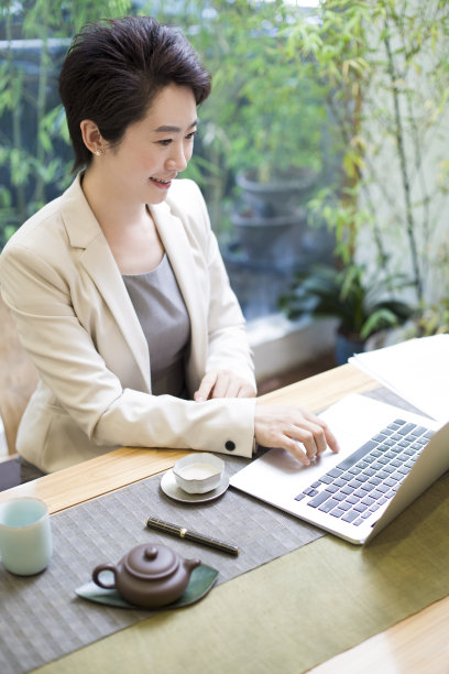商务女性在茶馆使用笔记本电脑工作图片下载