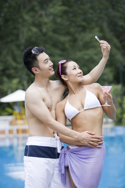 年轻情侣在泳池边拍照图片下载