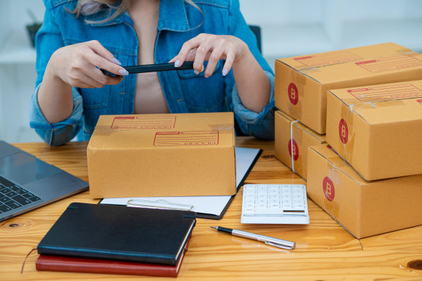 小型企业企业家，创业，中小企业，年轻的亚洲人工作，和航运集装箱包装在线市场中小企业电子商务销售商的想法包装和检查客户订单在笔记本电脑在家里。图片下载