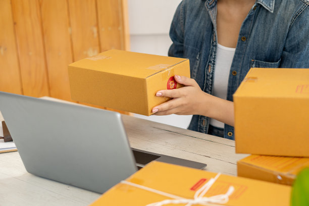 小型企业企业家，创业，中小企业，年轻的亚洲人工作，和航运集装箱包装在线市场中小企业电子商务销售商的想法包装和检查客户订单在笔记本电脑在家里。图片下载