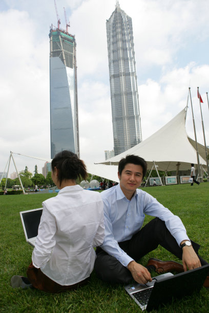 上海浦东金茂大厦前草坪上两位商务人士使用笔记本电脑图片下载