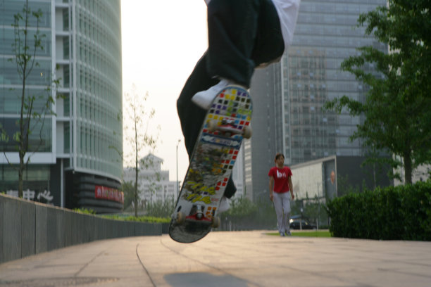 男青年在写字楼下玩滑板，腿部特写图片下载