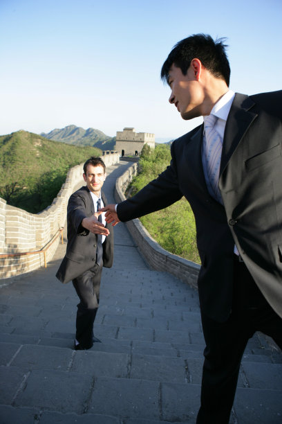 中国商务人士帮助外国商务人士攀登长城图片下载