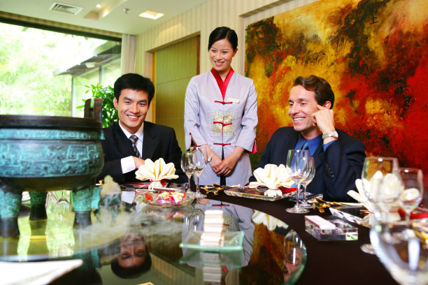 中外商务人士坐在酒店餐桌旁把玩工艺品图片下载