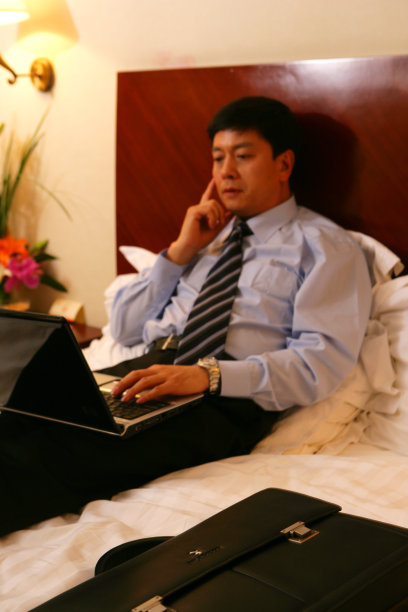 商务人士在酒店床上使用笔记本电脑图片下载