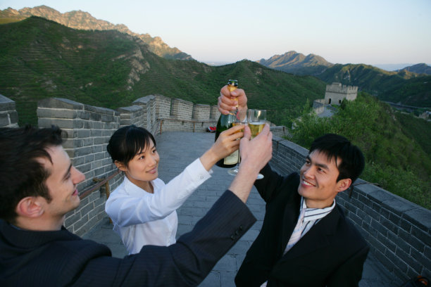 三位中外商务人士在长城上举杯庆贺图片下载