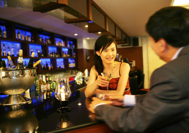 一对男女在酒店酒吧里饮酒交谈图片下载