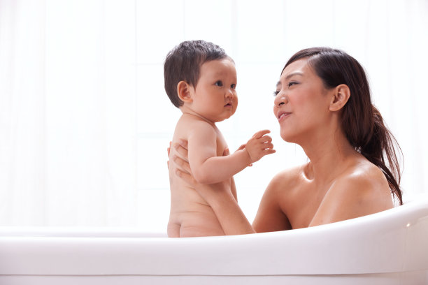 母亲和婴儿坐在浴缸中洗澡图片下载