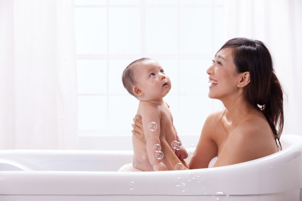 母亲和婴儿坐在浴缸中洗澡图片下载