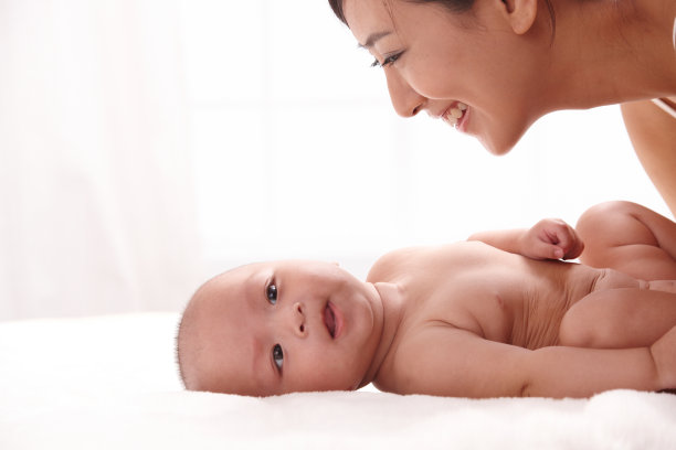 母亲和婴儿面对面躺在床上图片下载
