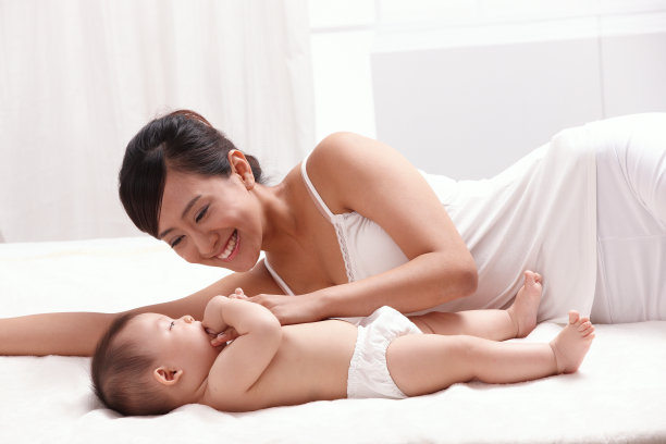 母亲和婴儿面对面躺在床上图片下载