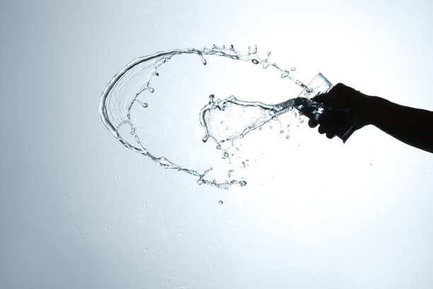 手拿杯子倒出的水花图片下载