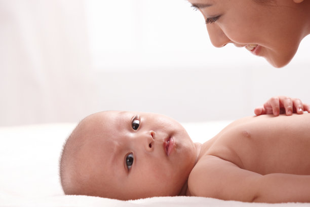 母亲和婴儿面对面躺在床上图片下载