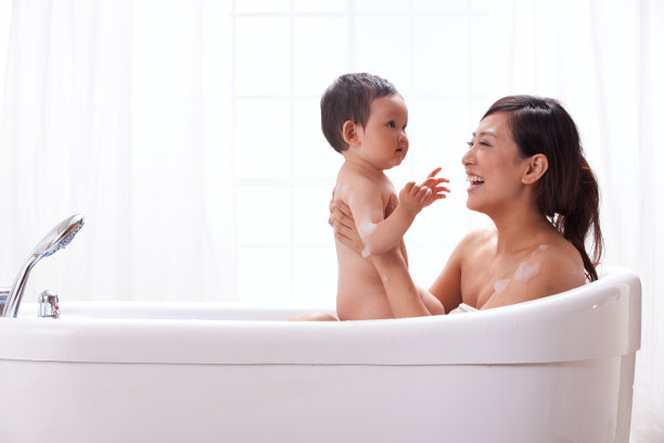 母亲和婴儿坐在浴缸中洗澡图片下载