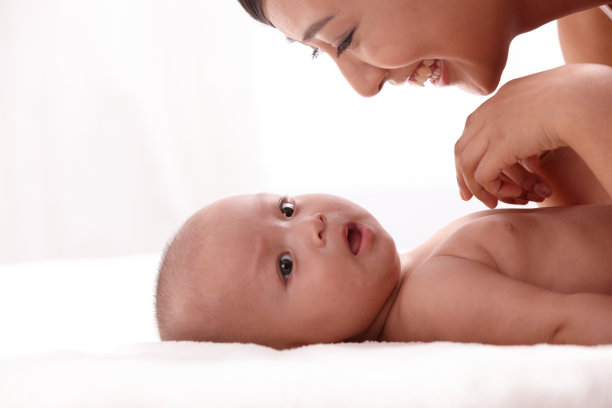 母亲和婴儿面对面躺在床上图片下载