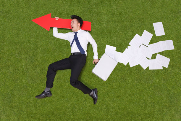 年轻男子手拿公文包躺在草地上图片下载