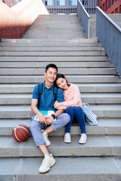 甜蜜的大学生情侣坐在楼梯上图片下载