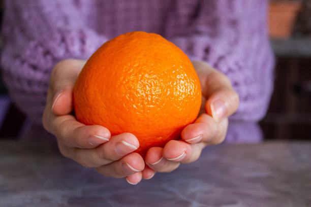 一个女人手里拿着橘子水果的特写照片。图片下载
