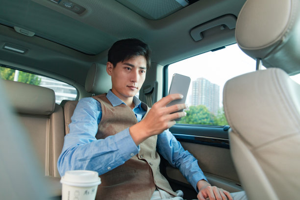 坐在汽车里看手机的商务男士图片下载