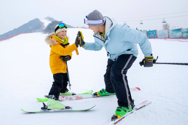 滑雪场上击掌的快乐父子图片下载