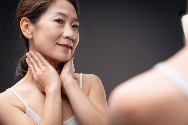 中年女人对着镜子做颈部护理图片下载