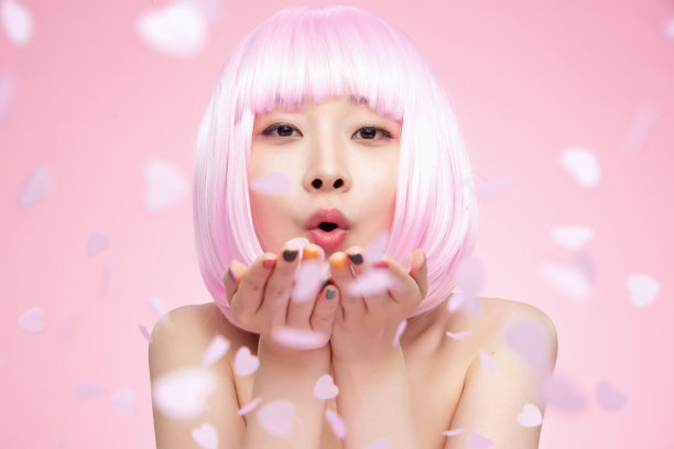 年轻女孩吹撒手中的心形纸片图片下载