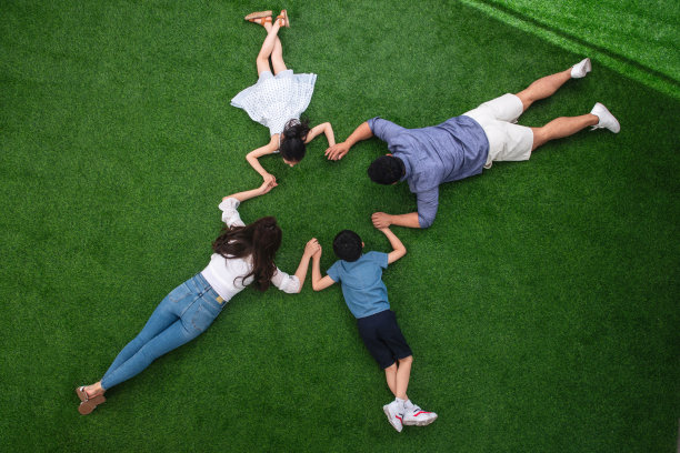 幸福的一家四口手牵着手趴在草地上图片下载