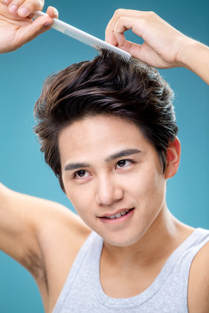 拿着梳子自己给头发做造型的年轻男人图片下载