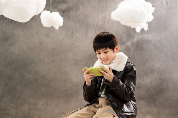 小男孩坐着玩游戏机图片下载