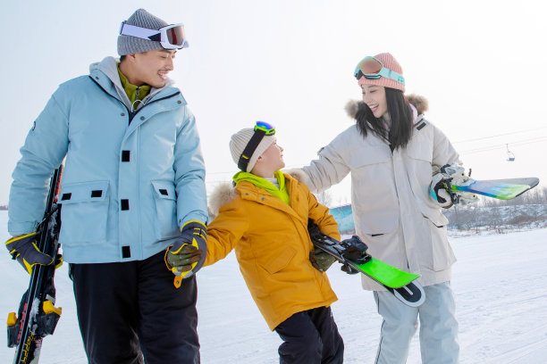 雪场上拿着滑雪板行走的一家三口图片下载