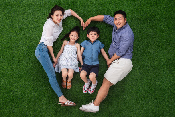 幸福的四口之家躺在草地上组成心形图片下载