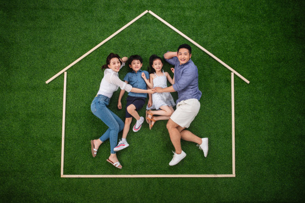 幸福的四口之家躺在草地上的房子轮廓里图片下载