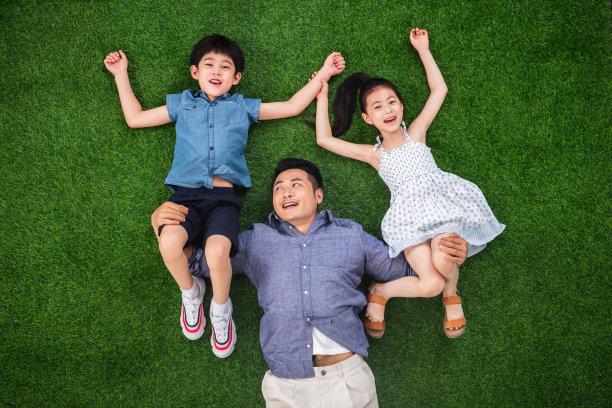 在草地上父亲托举儿子和女儿图片下载