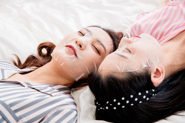 年轻闺蜜躺在床上敷面膜图片下载