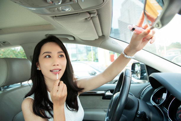 漂亮的青年女人对着后视镜化妆图片下载