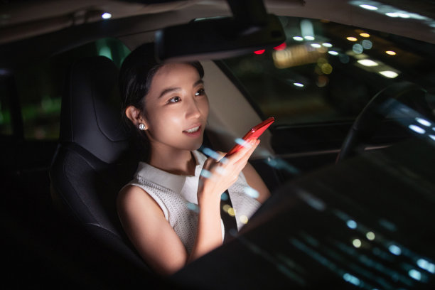 青年女人坐在汽车里使用手机图片下载