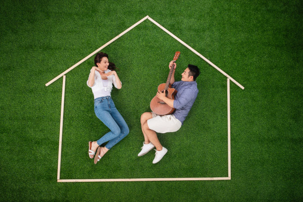 青年伴侣躺在草地上的房子轮廓里唱歌跳舞图片下载