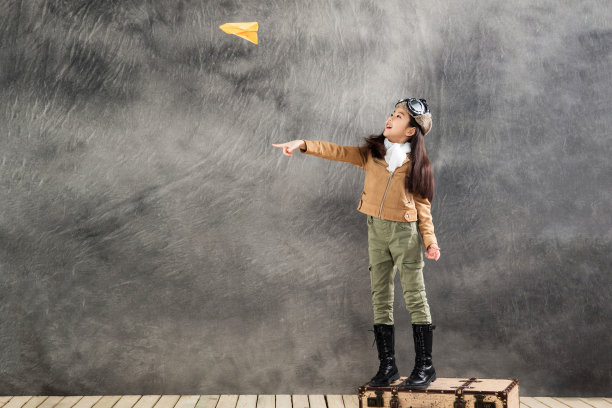 站在行李箱上扔纸飞机的小女孩图片下载