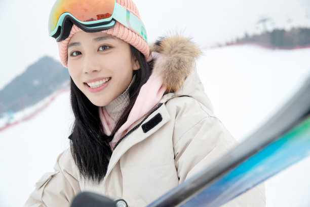 滑雪场上抱着滑雪板漂亮的青年女人图片下载