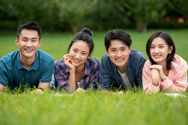 快乐的大学生趴在草地上素材图片