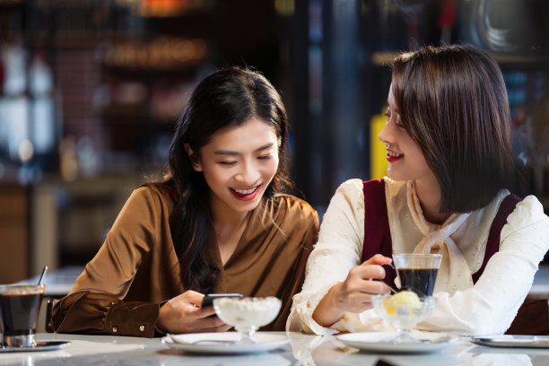 年轻闺蜜在咖啡馆使用手机图片下载