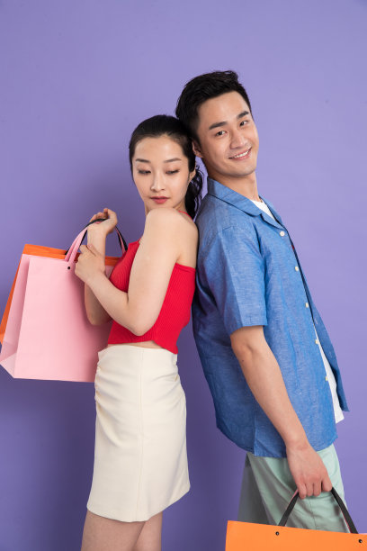 拎着购物袋背靠背的年轻情侣图片下载